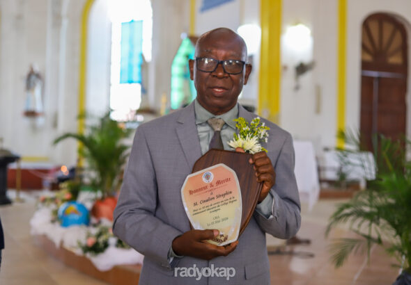 Le professeur Cinelien Séraphin avec sa plaque d’honneur remise par la direction du CRA. (Photo : Ketlain Difficile / Radyokap)